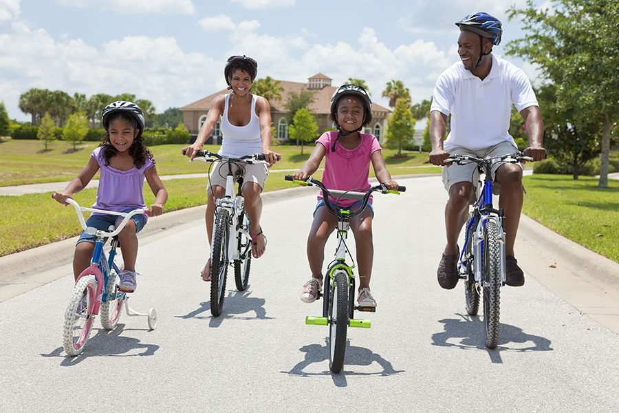 Employee Benefits - A Family and Their Two Small Daughters Riding Bikes Together on the Road on a Sunny Day